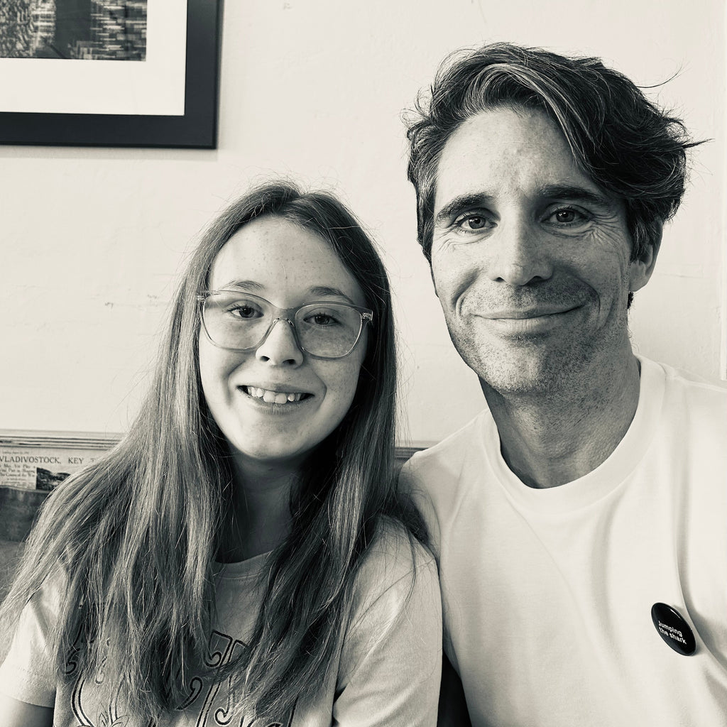 Black and white photo of a man and a girl sitting together indoors.
